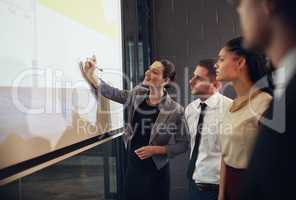 Getting her team involved in the business process. Shot of an executive giving a presentation on a projection screen to a group of colleagues in a boardroom.
