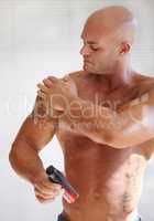 Getting ready for the comp. A muscular man applying a lotion to his skin.