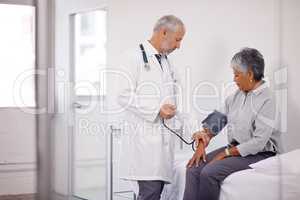 A routine checkup. A doctor measuring a mature patients blood pressure.
