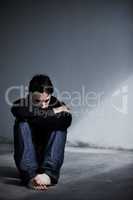 Dealing with emotional stress. A young man looking worried while sitting barefoot on the ground.