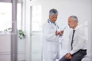 These should help a lot. A mature doctor giving a bottle of pills to one of her patients during a checkup.