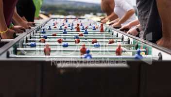 Foosball fanatics. Cropped shot of a group of people playing foosball.