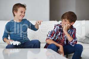 Haha, you lost again. Shot of a young boy laughing at his friend after beating him at a video game.