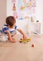 The wheels on the bus go round and round. Shot of a cute little boy playing with his toys in his room.