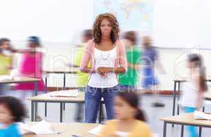 Shes the calm amidst the storm. Portrait of a young teacher with her students running around her.