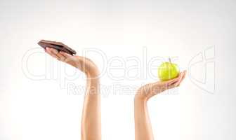 Why cant I choose both. Studio shot of an unrecognizable woman deciding between healthy and unhealthy foods against a grey background.