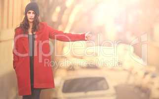 Stay well travelled in winter. Portrait of a gorgeous young woman in a red winter coat hailing a cab in the city.