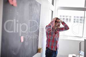 Sometimes you just have to let it out. Shot of young designer in his office, holding his head and screaming with frustration.