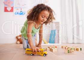 Vroom goes the school bus. Shot of a little girl playing with a toy truck and building blocks.