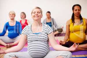 Meditating on motherhood. A multi-ethnic group of pregnant women meditating in a yoga class.