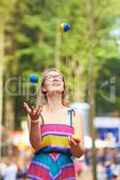 Her juggling skills are on the ball. Shot of an attractive young woman juggling at an outdoor festival.