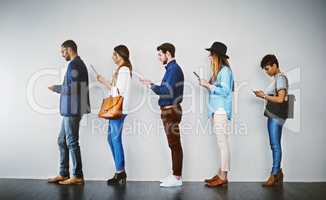 Getting last minute tips online before the interview. Shot of a group of businesspeople using wireless technology while waiting in line.