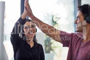 Always proving a quality customer service experience. Shot of two call centre agents giving each other a high five at the office.