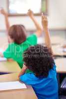 Theyre diligent students. Rearview shot of schoolchildren holding their hands up to answer a question in class.