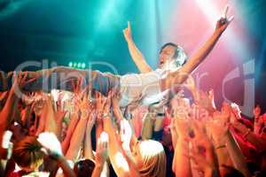 A young man cheering as he crowd surfs at a concert. This concert was created for the sole purpose of this photo shoot, featuring 300 models and 3 live bands. All people in this shoot are model released.