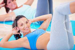Keeping her core strong. Young woman doing a sit up during a pilates class.