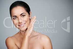 Soft and smooth yet. Cropped studio shot of a beautiful mid adult woman touching her face.