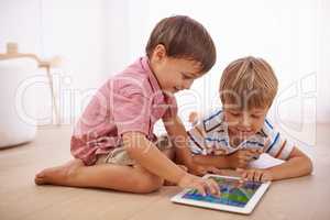 Showing him some tablet tricks. Shot of little boys playing on the floor.