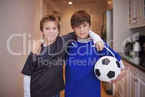 Boys will be boys. Portrait of two young boys in sports clothing standing indoors with a soccer ball.