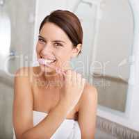 Shes all about dental hygiene. A gorgeous young brunette brushing her teeth in the morning.