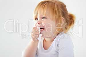 Not even a runny nose can dampen the giggles. A cute baby girl laughing while holding a tissue.