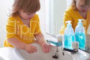 Look, its running through my fingers. An adorable little girl washing her hands in the bathroom.