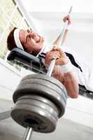 He has a big weight on his chest. A young man struggling to lift some heavy weights at the gym.