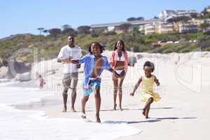 Im winning the race. A happy young african family running energetically along the beach.