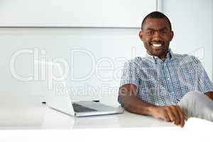 Thanks to technology, my client base is constantly increasing. A handsome ethnic businessman seated at a desk alongside a laptop.