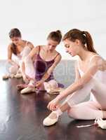 Getting ready to dance. Young teen ballet dancers fastening their slippers before a class.