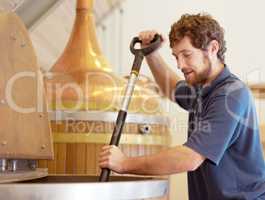 Brewing the best. Shot of a young man working on a batch of beer in a brewery.