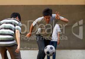 Dribbling to the goal. Young asian males playing soccer outside.