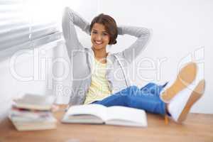 Happy to be having a break. Shot of a cute young college student with her feet up and hands behind her head.