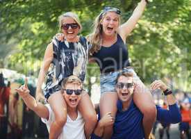 Getting a better look at the band. Two guys carrying their girlfriends on their shoulders at a music festival.