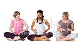 Sharing their experiences. Pregnant friends sitting together in a row while isolated on white.