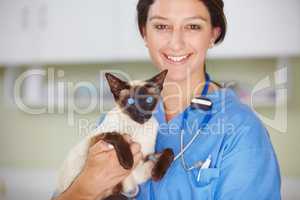 Taking great care that your animals have the best chance possible. Portrait of a smiling female vet holding a Siamese cat.