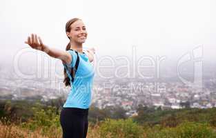 Can you smell that crisp morning air. Shot of a young woman training outdoors with her arms outstretched.