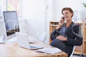 Taking some friendly baby advice. A pregnant businesswoman having an enjoyable conversation on the phone at her office desk.
