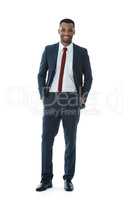 Positivity brings him success. A smiling businessman with his hands in his pockets while isolated on white.