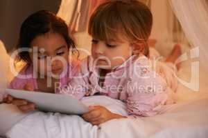 I LOVE sleepovers. Shot of two cute little girls reading a story together.