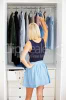 Considering her choices. Rear-view of a young woman choosing an outfit in her closet.