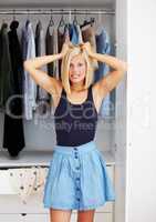 Her closets full, but she has nothing to wear. Frustrated young woman standing with her hands in her hair in front of her wardrobe.