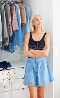 Picturing the perfect outfit. Young woman standing with her arms folded in front of a wardrobe and looking contemplative.