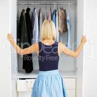 Closet full of choices. Rear-view of a young blonde woman choosing an outfit in her closet.