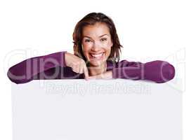 Presenting your copy. Studio shot of an attractive woman in her 30s leaning on a placard while pointing and smiling at the camera.