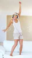 Dancing to the sound. A young woman dancing around while listening to songs on her headphones.