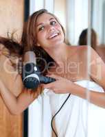 Blowdrying my hair after a shower. An attractive young woman blow drying her hair.