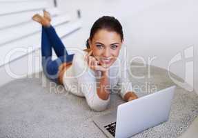 Never far from social media. A beautiful young woman sitting on her floor and using a laptop.