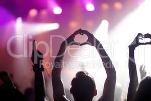 Showing some love for the band. Rearview of people in the audience at a music concert holding up their hands in a heart symbol.