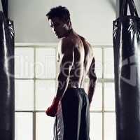 Hes dedicated to the sport of boxing. Portrait of a handsome young boxer standing in the gym.